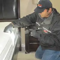 Bed bug inspection technician checking a mattress and bed frame for signs of infestation in Tacoma, WA
