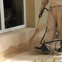 General pest control technician spraying exterior perimeter around a home in Tacoma, WA