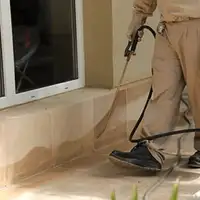 General pest control technician spraying exterior perimeter around a home in Tacoma, WA