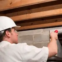 Termite inspection technician checking a basement wall and framing for termite activity in Tacoma, WA